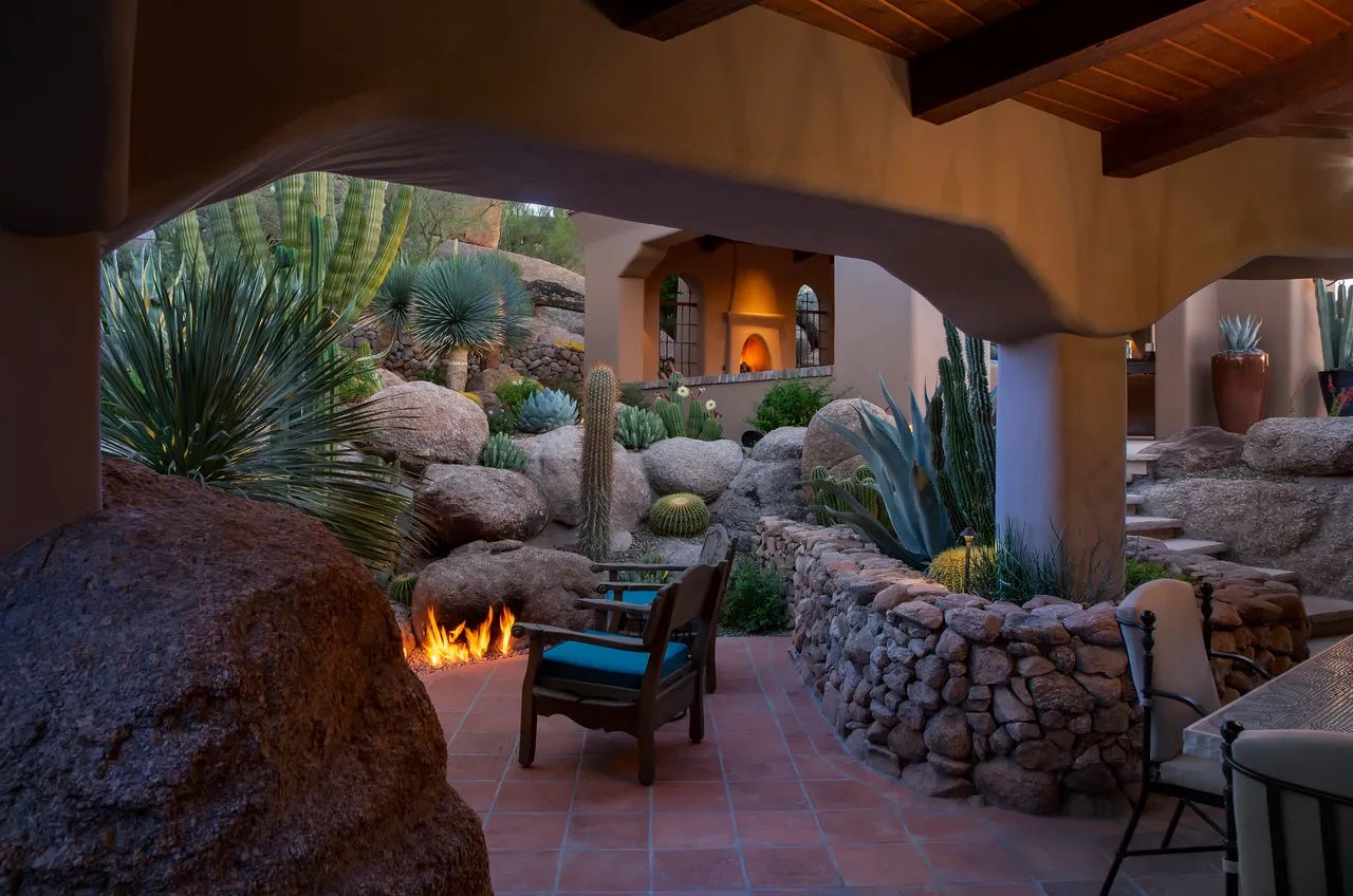 A patio with chairs and fire pit in the middle of it.