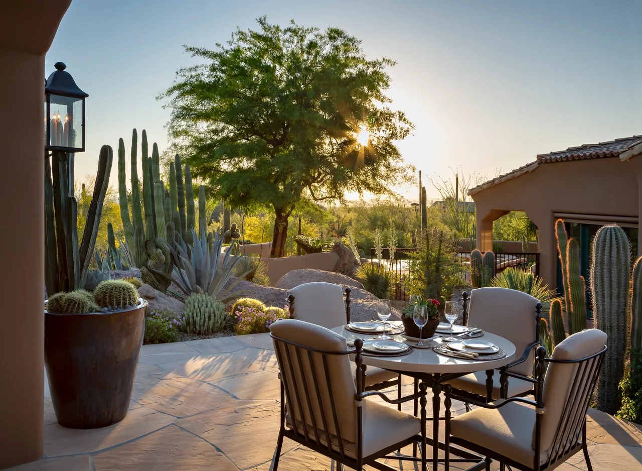 A patio with chairs and tables in the middle of a yard.